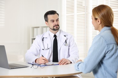 Cardiologist consulting patient at table in clinic