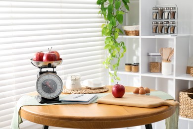 Photo of Retro mechanical kitchen scale, products and stationery on wooden table indoors