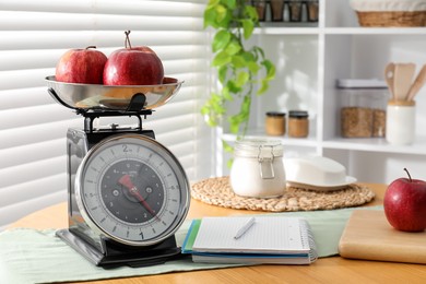 Photo of Retro mechanical kitchen scale, products and stationery on wooden table indoors