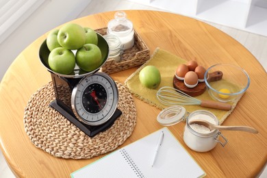 Retro mechanical kitchen scale, products and stationery on wooden table indoors