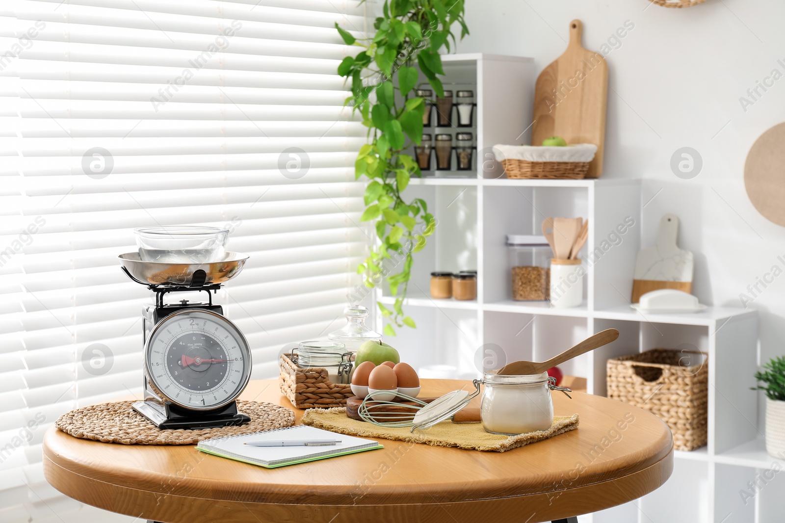 Photo of Retro mechanical kitchen scale, products and stationery on wooden table indoors