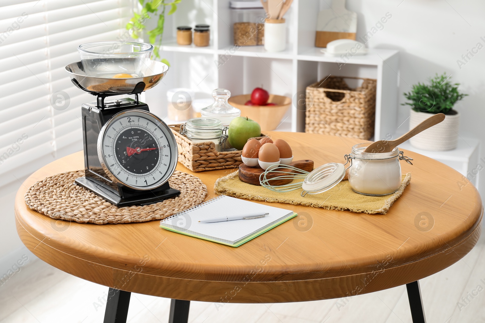 Photo of Retro mechanical kitchen scale, products and stationery on wooden table indoors