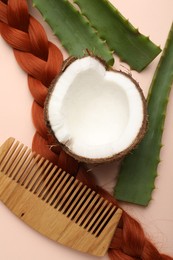 Photo of Hair treatment. Fresh coconut, comb, braided hair lock and aloe leaves on beige background, flat lay