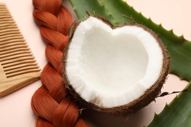 Photo of Hair treatment. Fresh coconut, comb, braided hair lock and aloe leaves on beige background, closeup