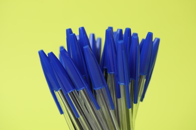 Photo of Many ballpoint pens on green background, closeup