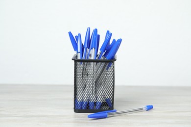 Photo of Many ballpoint pens in holder on wooden table