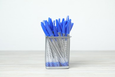 Photo of Many ballpoint pens in holder on wooden table