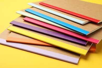 Photo of Many different copybooks on yellow background, closeup