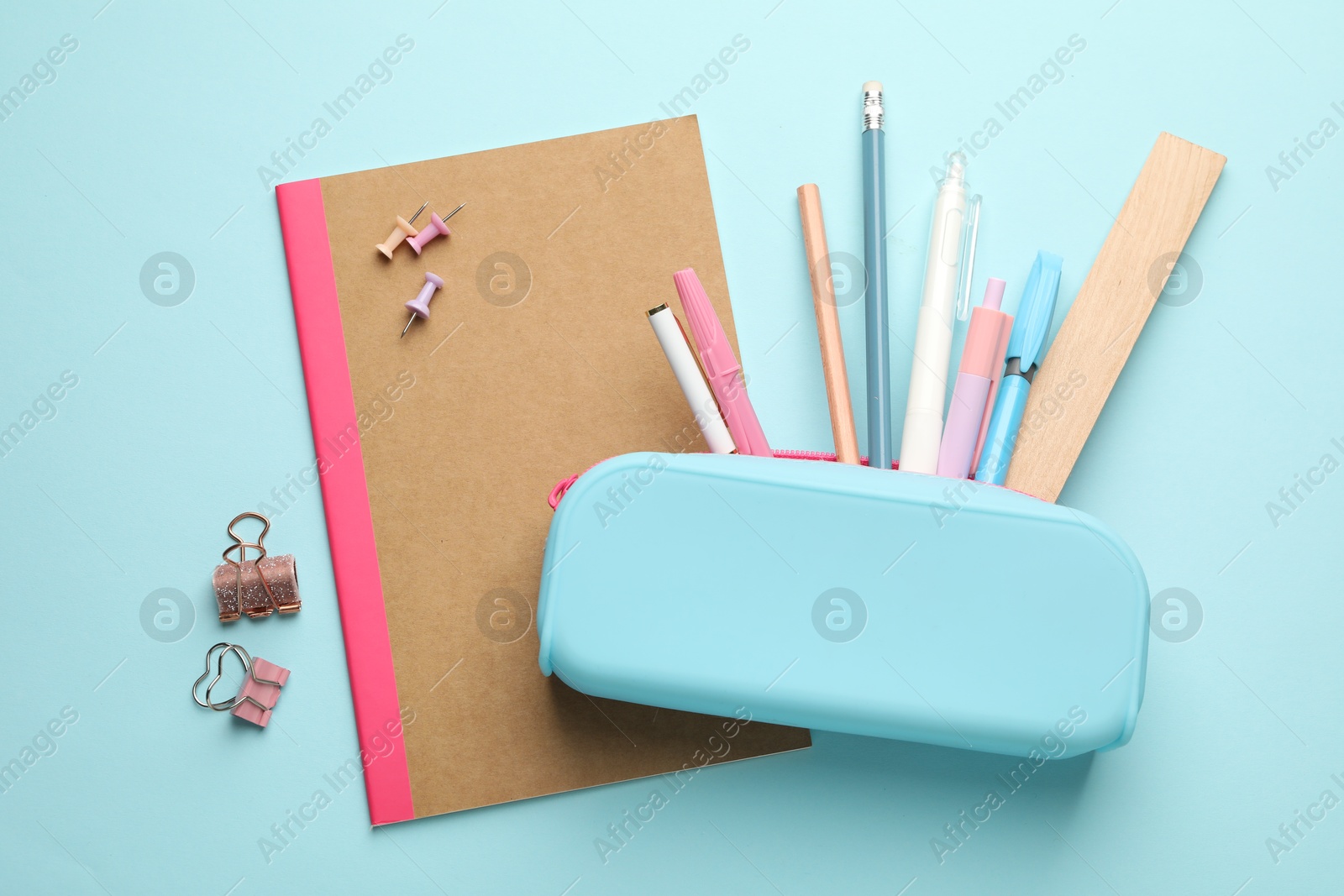 Photo of Copybook and other different stationery on light blue background, flat lay