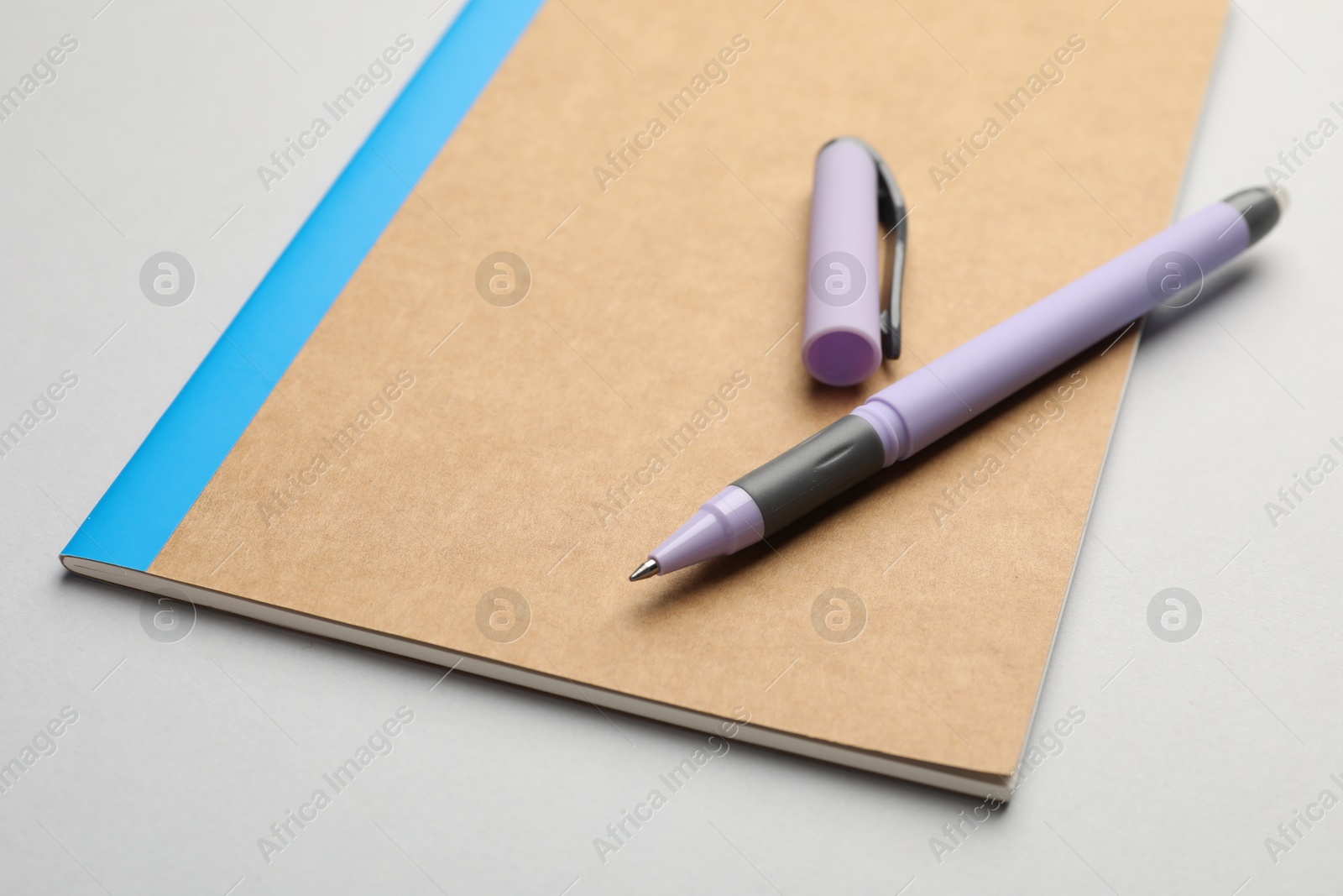 Photo of Copybook and pen on grey background, closeup