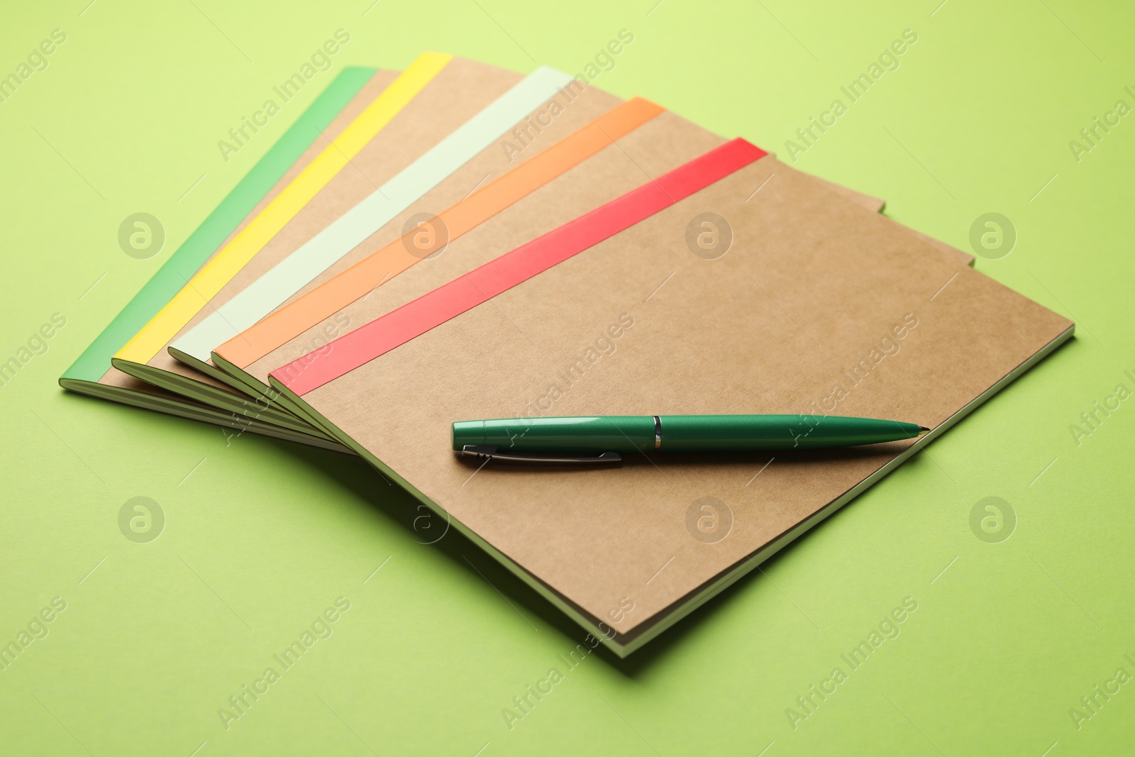 Photo of Different copybooks and pen on green background, closeup