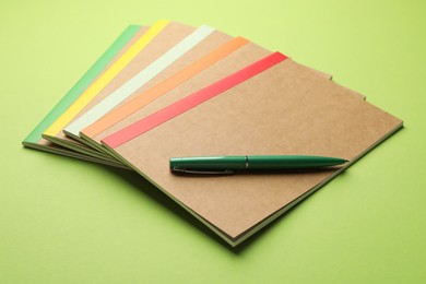 Photo of Different copybooks and pen on green background, closeup