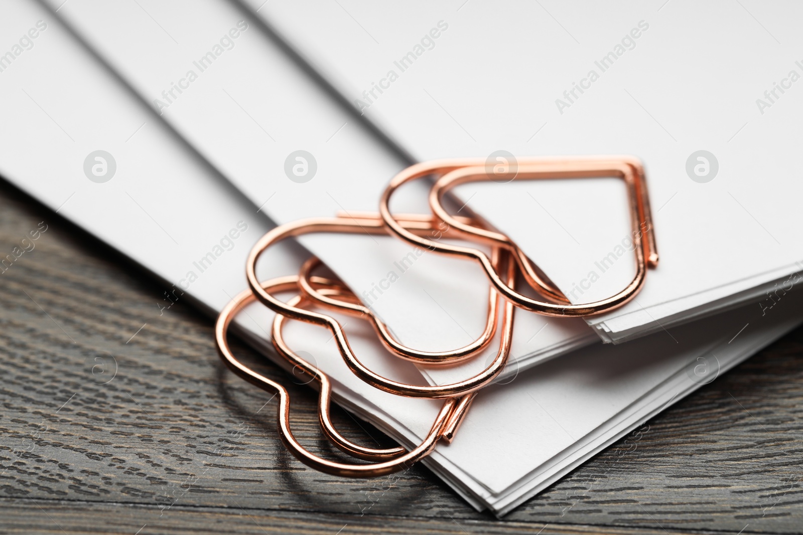 Photo of Metal paper clips and notes on wooden table, closeup