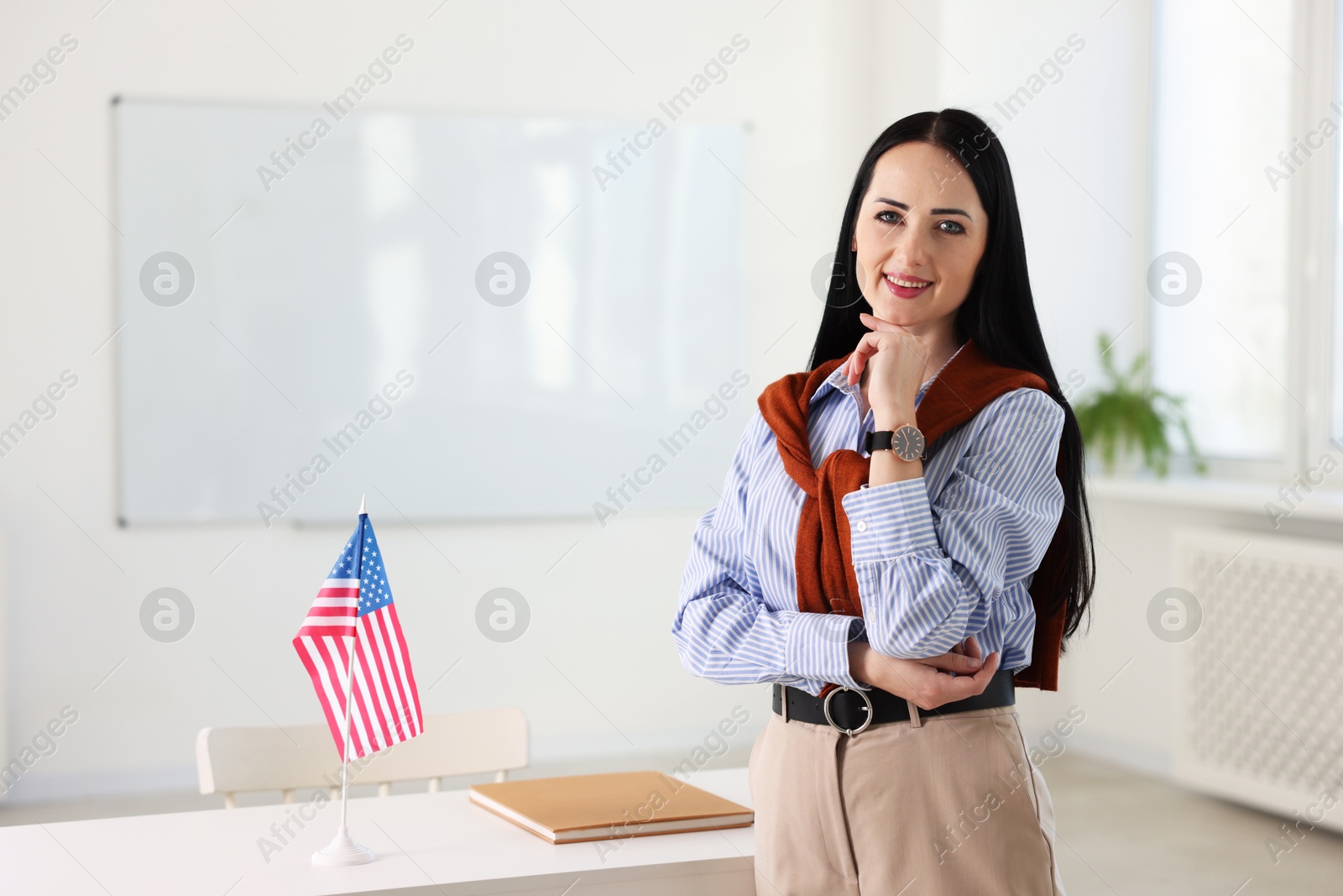 Photo of Portrait of English teacher at desk in classroom. Space for text