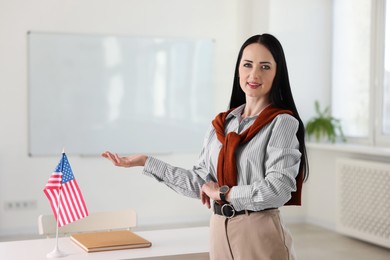 Photo of Portrait of English teacher at desk in classroom. Space for text