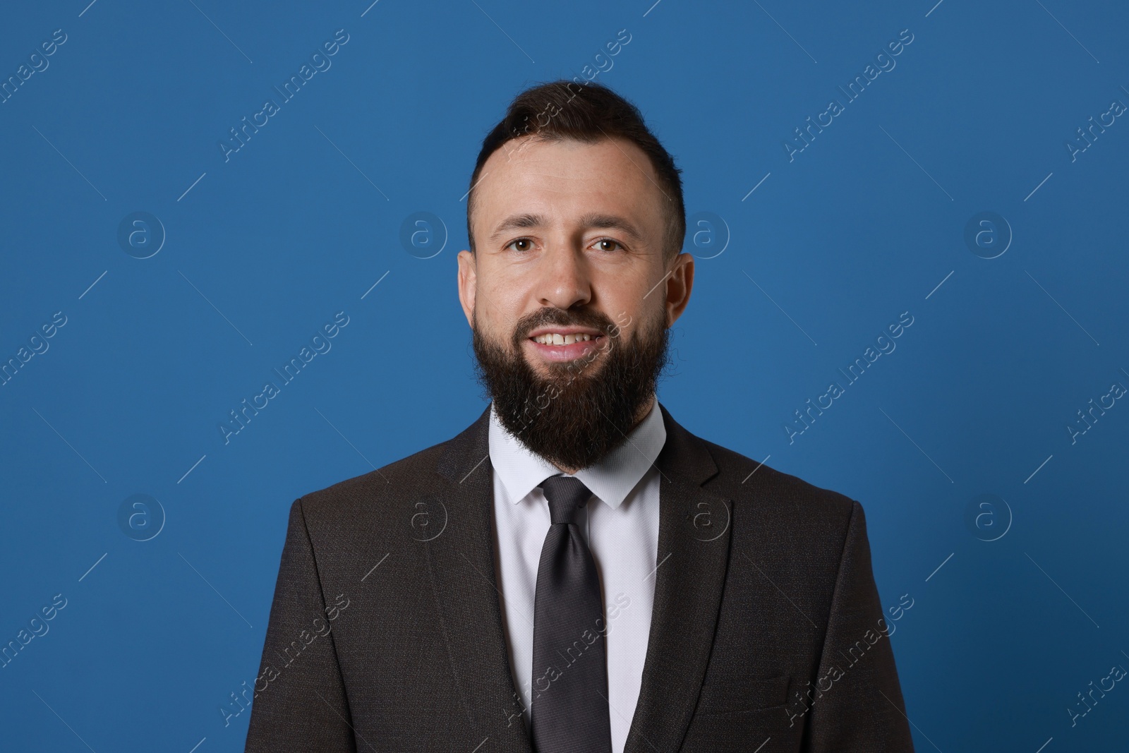 Photo of Handsome bearded man in suit on blue background