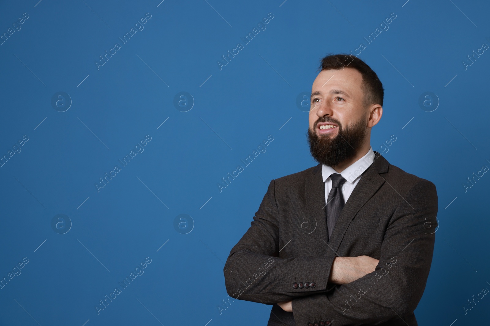 Photo of Handsome bearded man in suit on blue background. Space for text