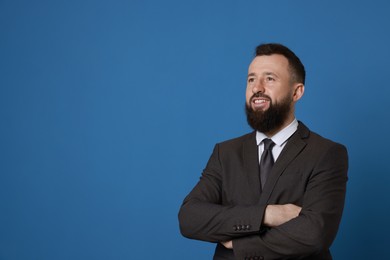 Photo of Handsome bearded man in suit on blue background. Space for text