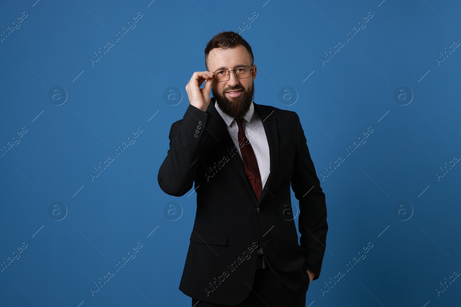 Photo of Handsome bearded man in suit on blue background