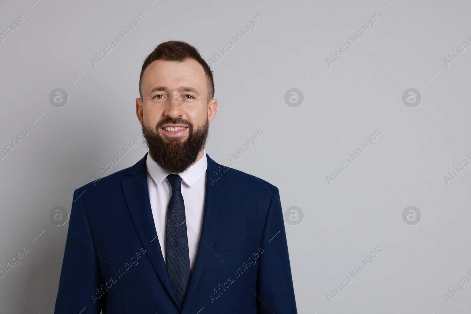 Photo of Handsome bearded man in suit on grey background. Space for text