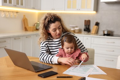 Photo of Work-family balance. Single mother with her daughter at wooden table in kitchen