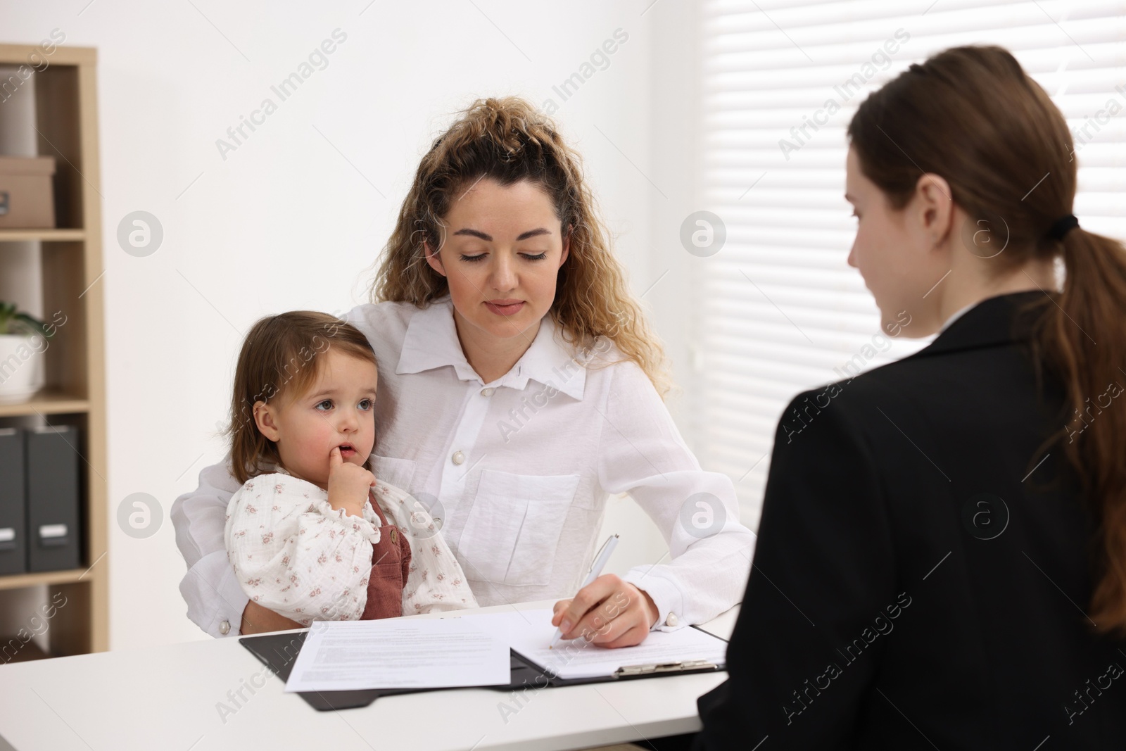 Photo of Single mother with her daughter during job interview at table indoors