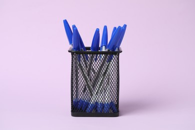 Photo of Many ballpoint pens in holder on pink background