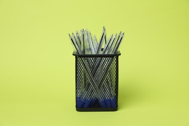 Photo of Many ballpoint pens in holder on green background