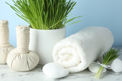 Photo of Spa composition with wheatgrass on white marble table, closeup