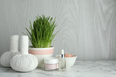 Photo of Spa composition with wheatgrass on white marble table. Space for text