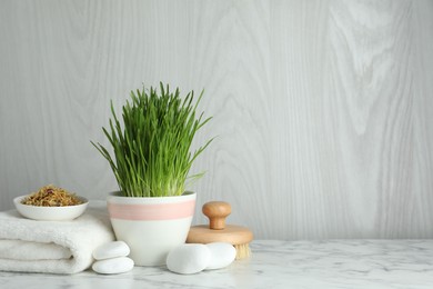 Photo of Spa composition with wheatgrass on white marble table. Space for text