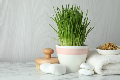 Photo of Spa composition with wheatgrass on white marble table. Space for text