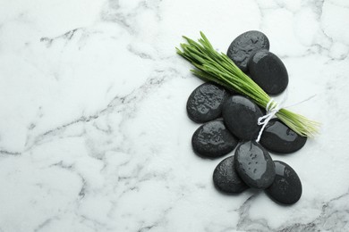 Photo of Spa stones and wheatgrass on white marble background, flat lay. Space for text