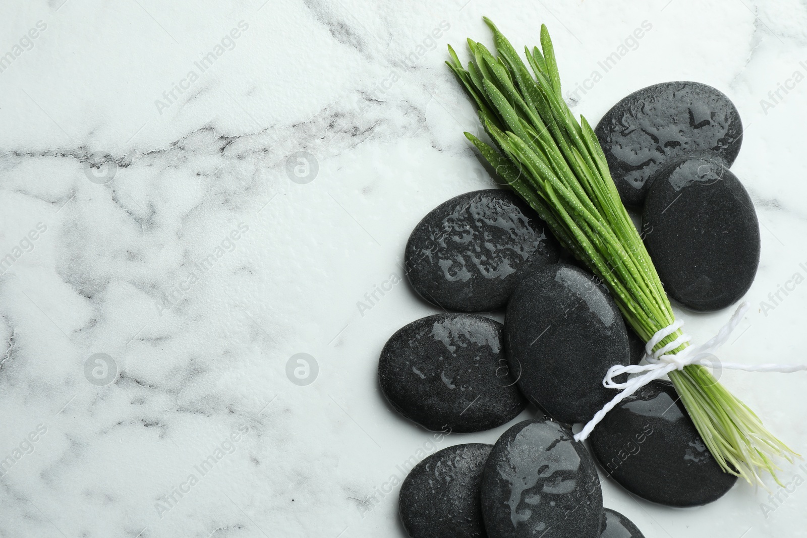 Photo of Spa stones and wheatgrass on white marble background, flat lay. Space for text