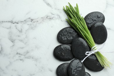 Spa stones and wheatgrass on white marble background, flat lay. Space for text