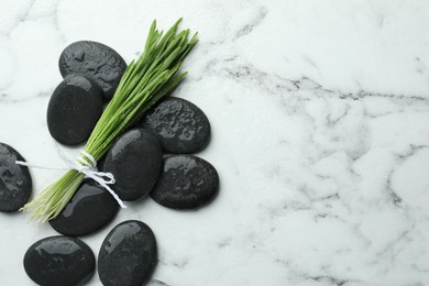 Photo of Spa stones and wheatgrass on white marble background, flat lay. Space for text