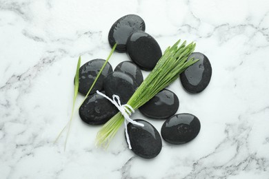 Photo of Spa stones and wheatgrass on white marble background, flat lay