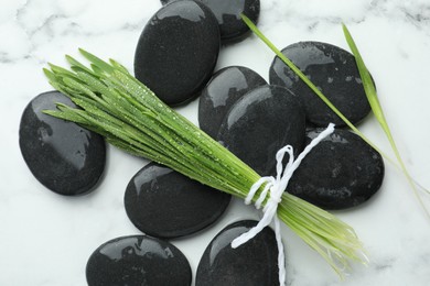 Photo of Spa stones and wheatgrass on white marble background, flat lay