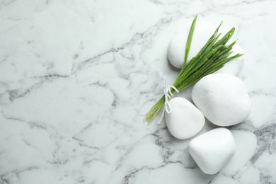 Photo of Spa stones and wheatgrass on white marble background, flat lay. Space for text