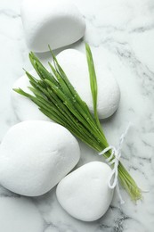 Spa stones and wheatgrass on white marble background, closeup