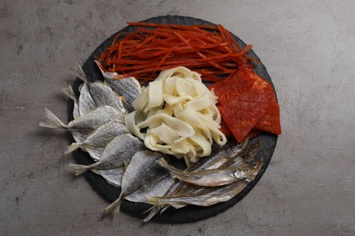 Photo of Many different dried fish snacks on grey table, top view