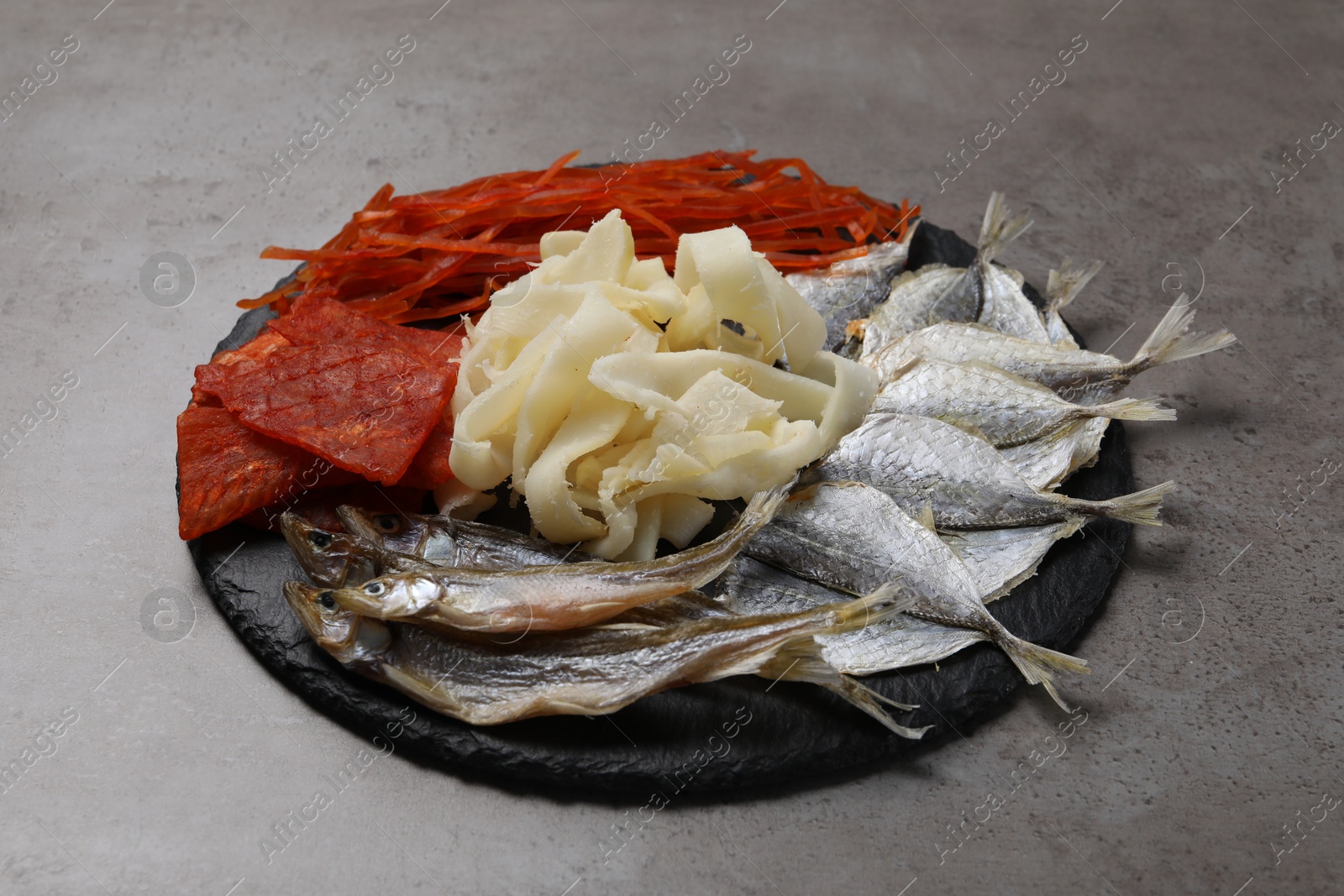 Photo of Many different dried fish snacks on grey table