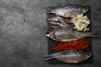 Photo of Many different dried fish snacks on grey table, top view. Space for text