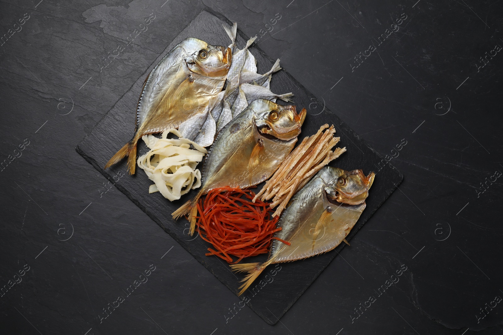 Photo of Many different dried fish snacks on black table, top view