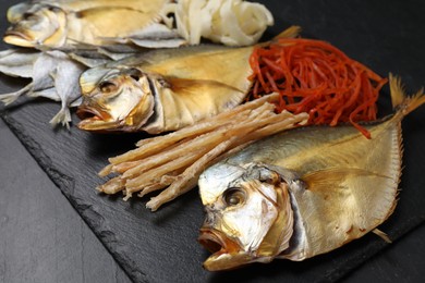 Many different dried fish snacks on black table, closeup