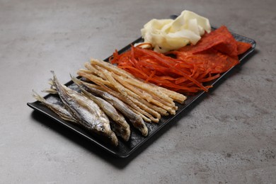 Photo of Many different dried fish snacks on grey table