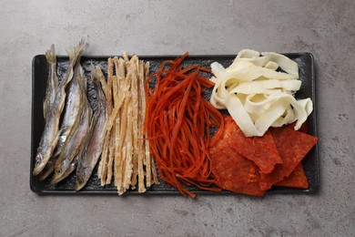 Photo of Many different dried fish snacks on grey table, top view