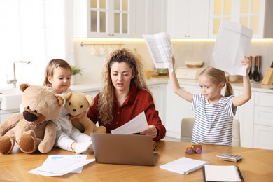 Photo of Work-family balance. Single mother with document and her daughters at table in kitchen