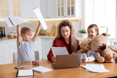 Photo of Work-family balance. Single mother with document and her daughters at table in kitchen