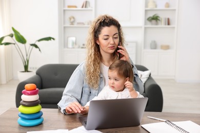 Photo of Work-family balance. Single mother talking on smartphone and her daughter at table indoors